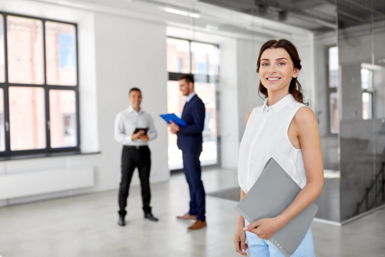 Smiling business woman with team in large office